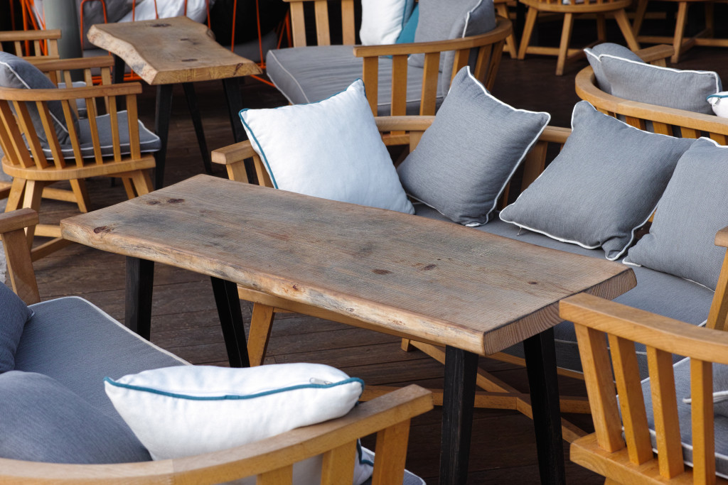 Wooden tables and chairs with pillows in street cafe