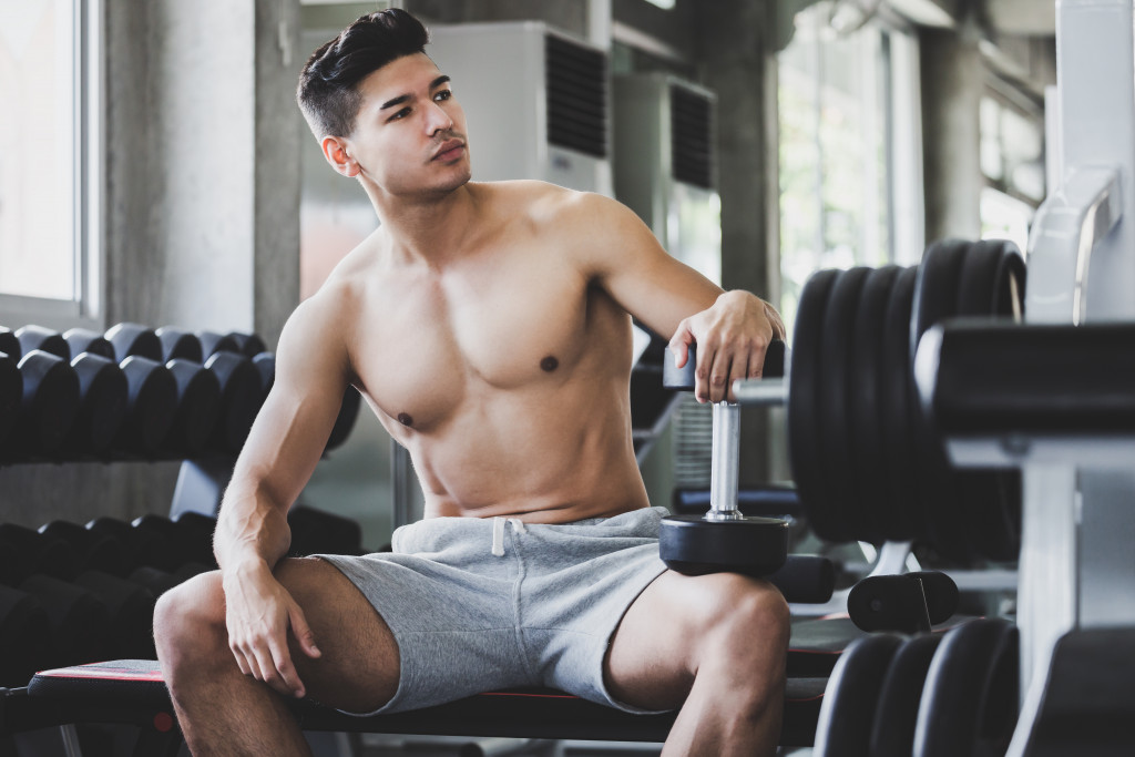 A handsome and muscular man without a shirt posing in the gym