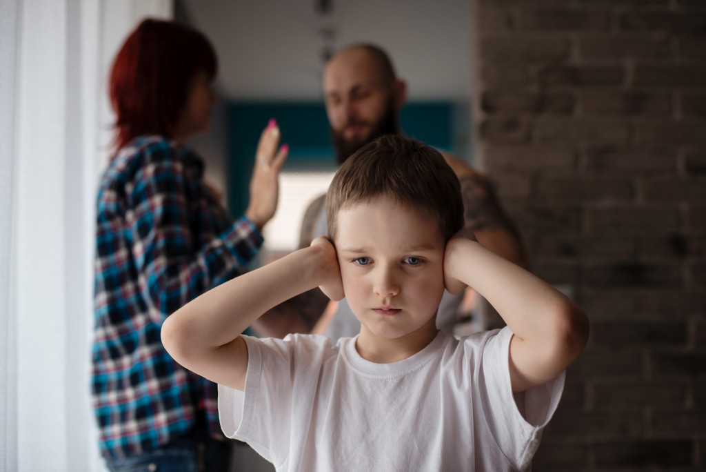 A child covering ears from parent argument