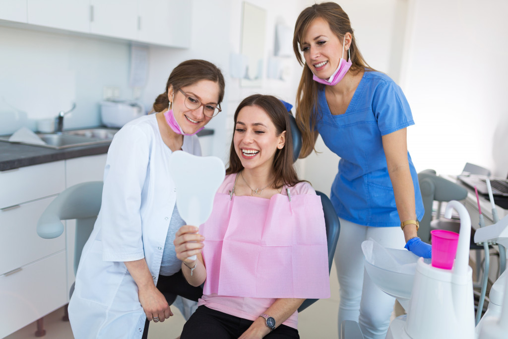 A patient in a dental clinic looking happy while looking in the mirror with friendly staff