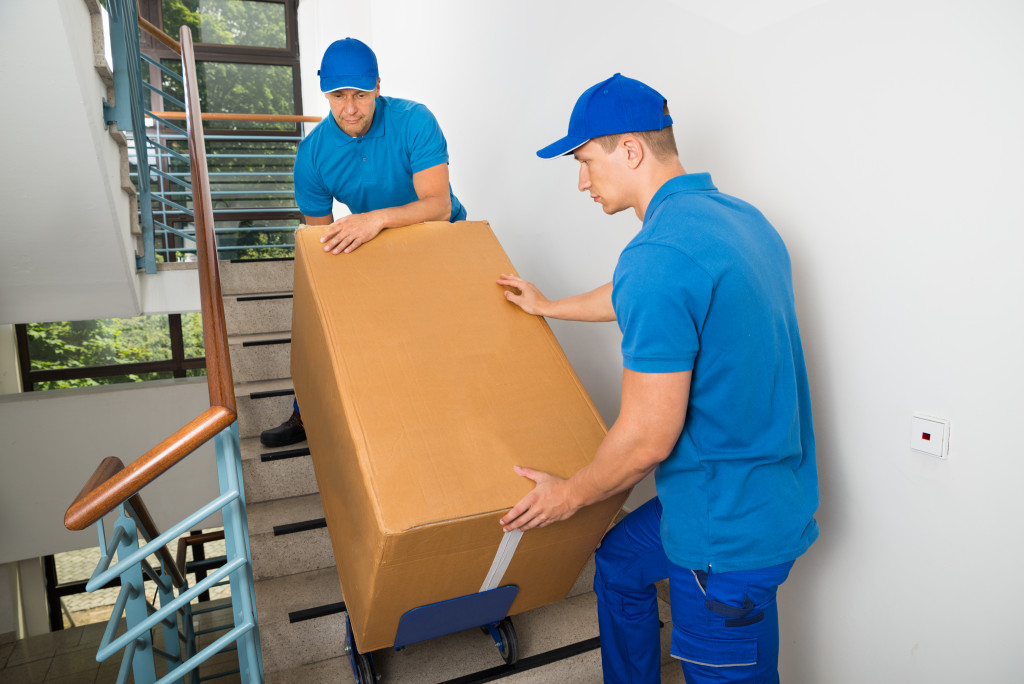 Two movers carrying a big box up the stairs