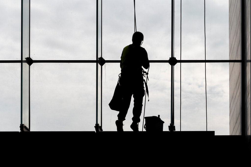 A working cleaning big windows in a building