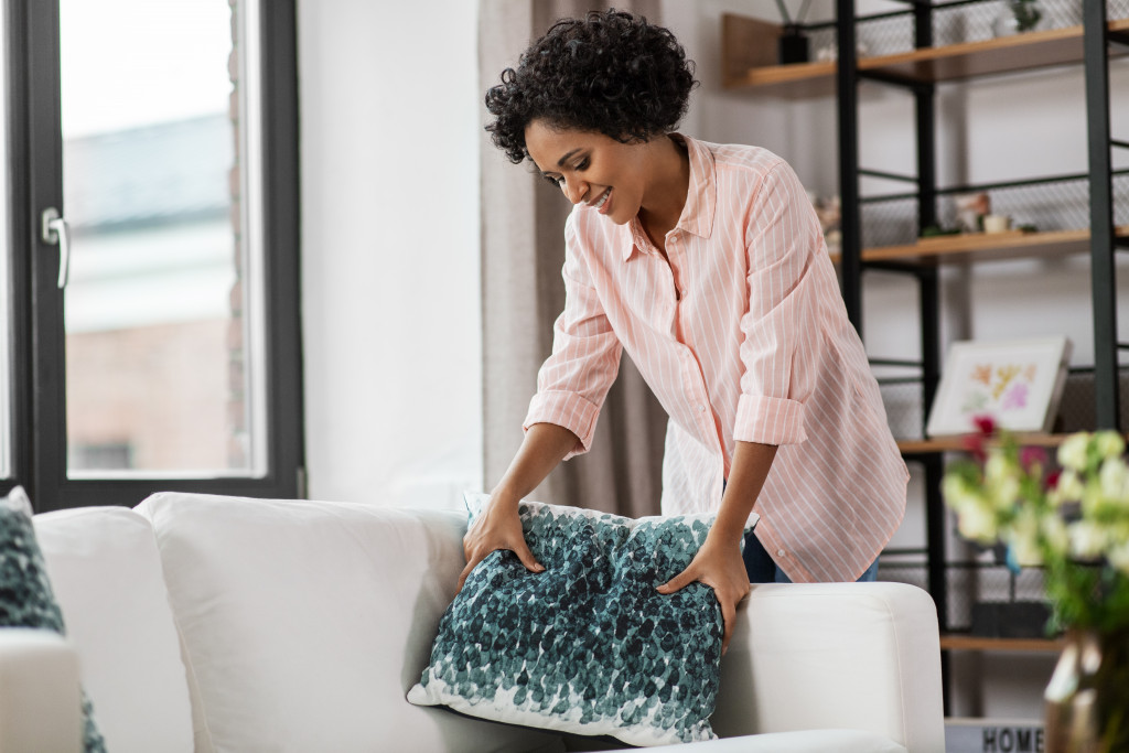 a woman adding decorative throw pillows