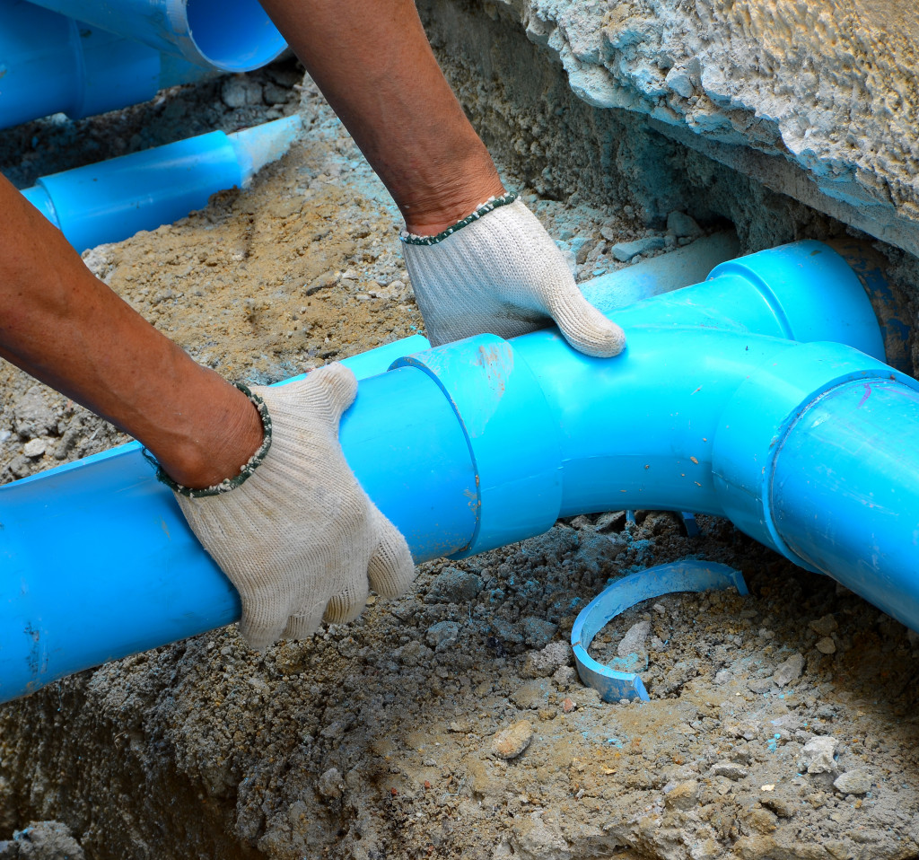 A man laying and checking PVC pipes outdoor