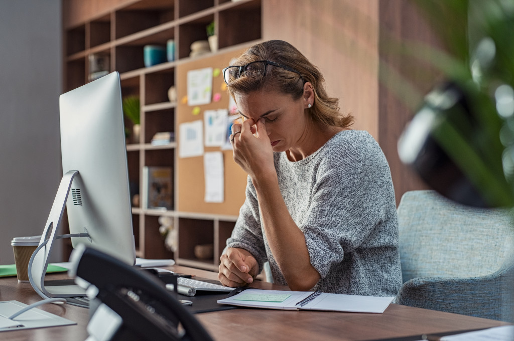  Mature creative woman working at office desk feeling tired