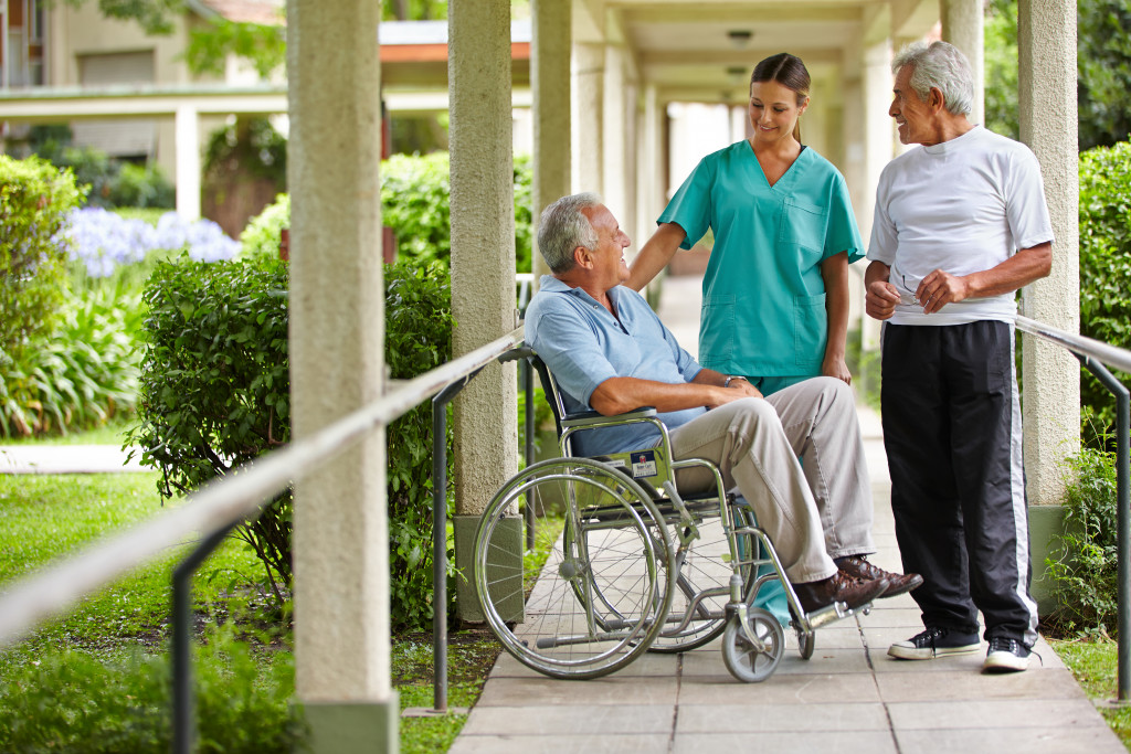 two senior men talking to a nurse in a walkway with handrails