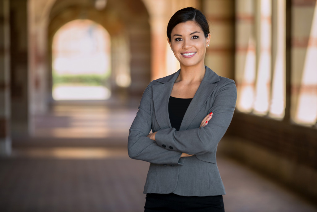 Smiling young woman standing with her arms cross in a hallway.