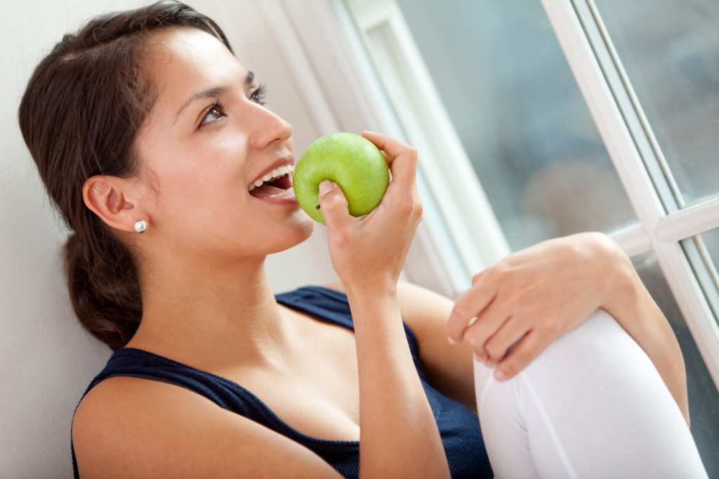 woman eating an apple by the window