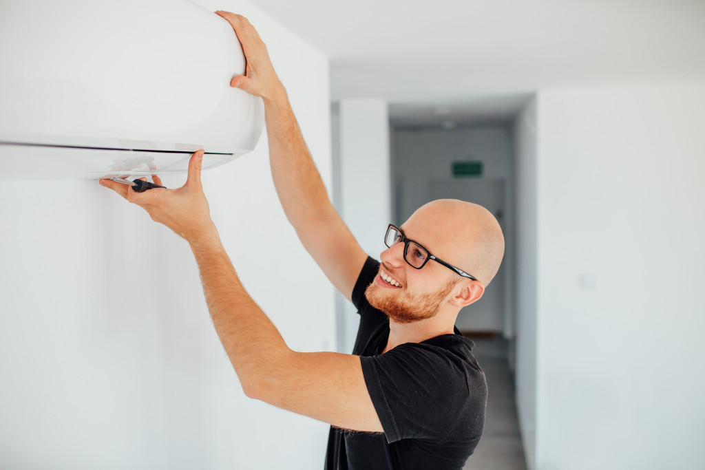 a man smiling while holding the aircon flap