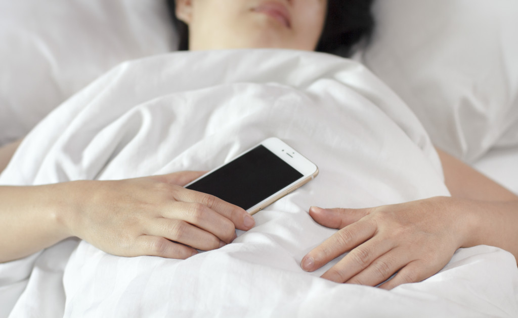 A person sleeping in a bed while holding a phone